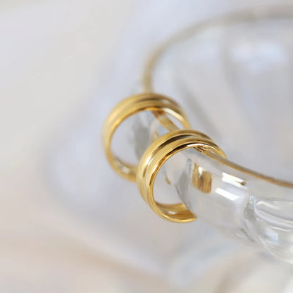 a different perspective of a pair of golden hoop earrings hanging on a glass