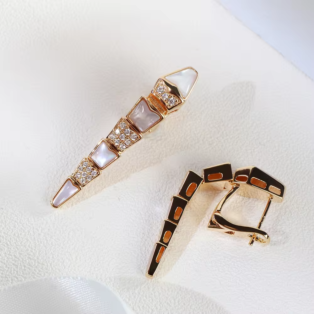 a pair of rose gold earrings with gemstones. one laying on its side to demonstrate how they are flexible.