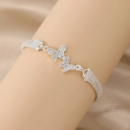 a silver bracelet with a butterfly design displayed on an arm