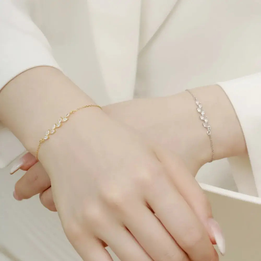 both gold and silver variant of a leaf bracelet being worn by a woman