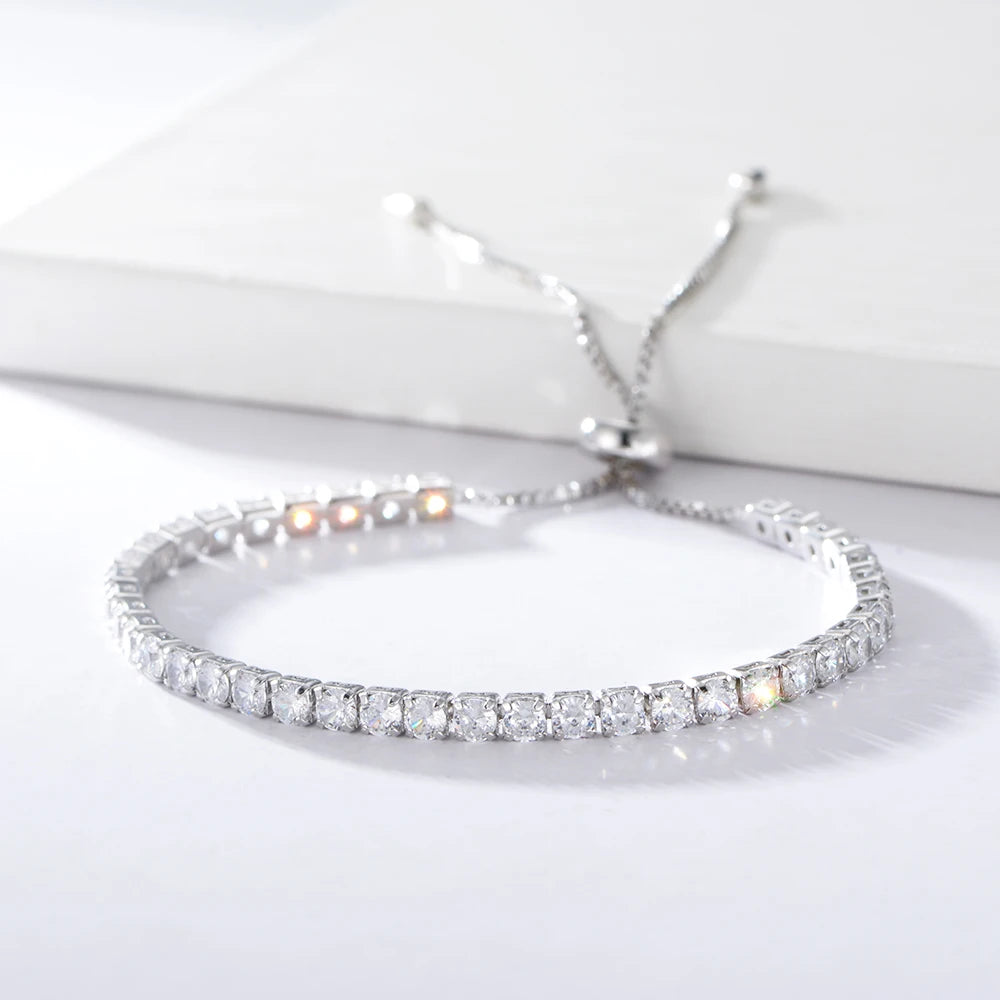 a silver tennis bracelet with radiant stones set on a silver chain, displayed against a white background with a box.