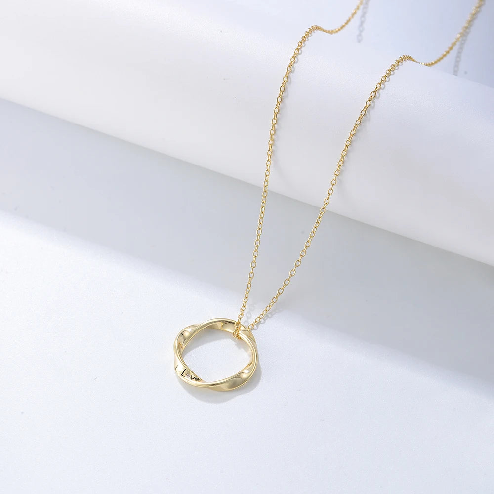 a golden necklace with a twisted ring on it