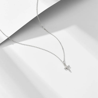 a silver cross necklace on a white surface