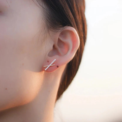a woman wearing a gold X shaped earrings