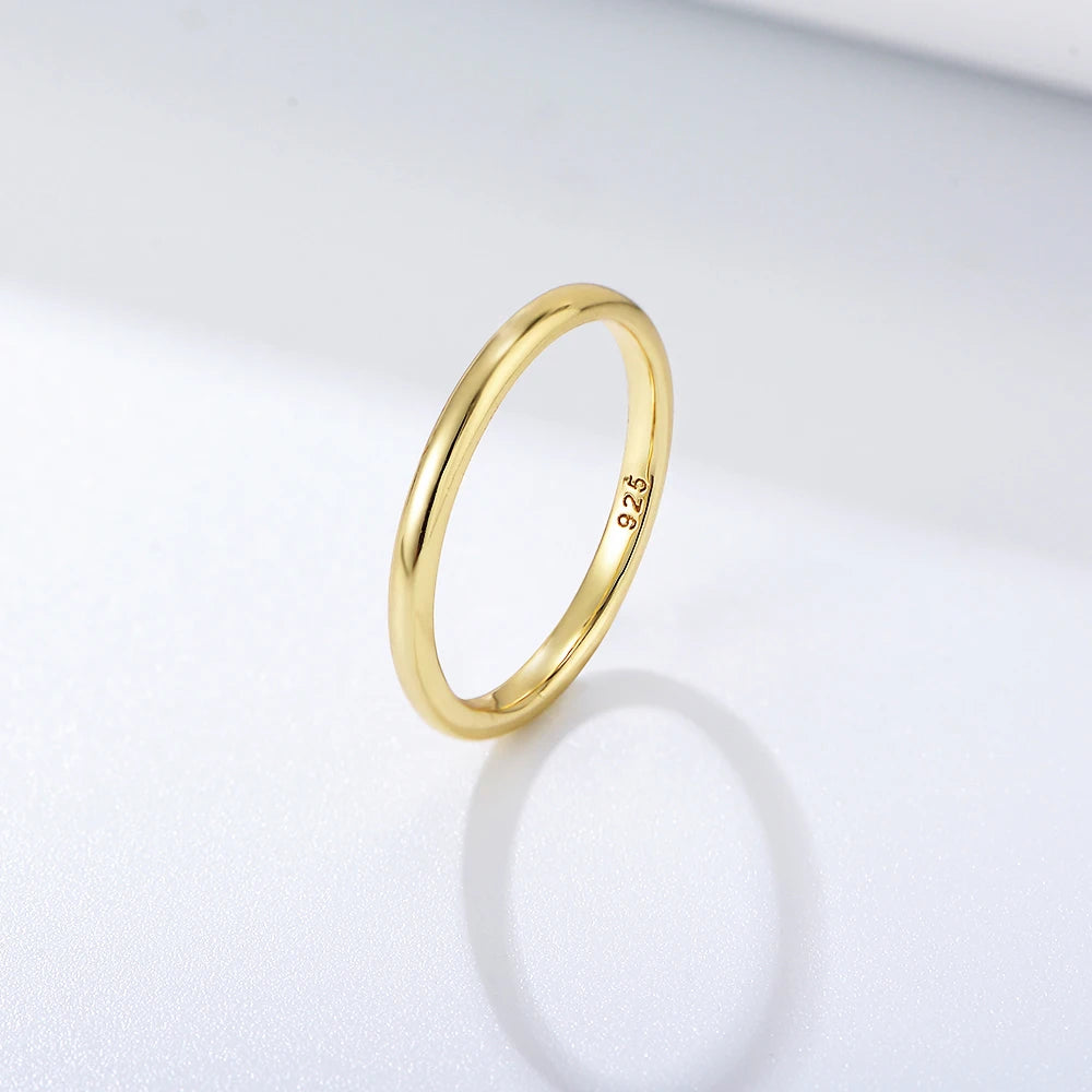 a plain gold ring on a white surface