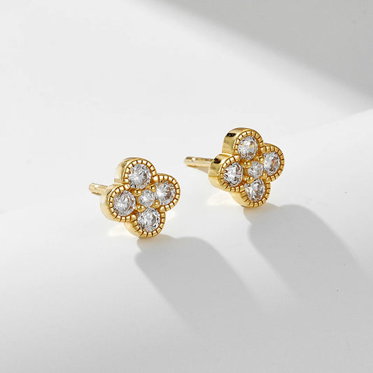 a pair of gold clover shaped earrings with gemstones set in each leaf