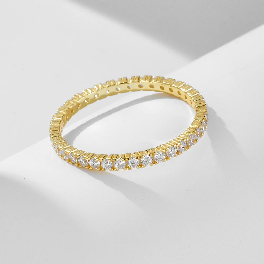 a gold ring set with fine gemstones all around tilted on a white surface