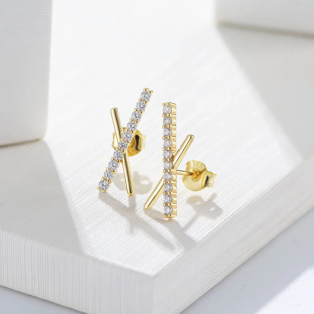 a pair of gold X shaped earrings with gemstones on one cross