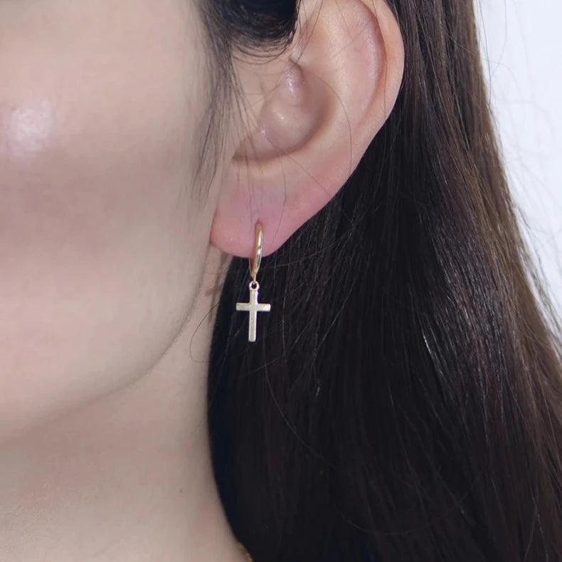 closeup of a woman wearing gold cross earrings