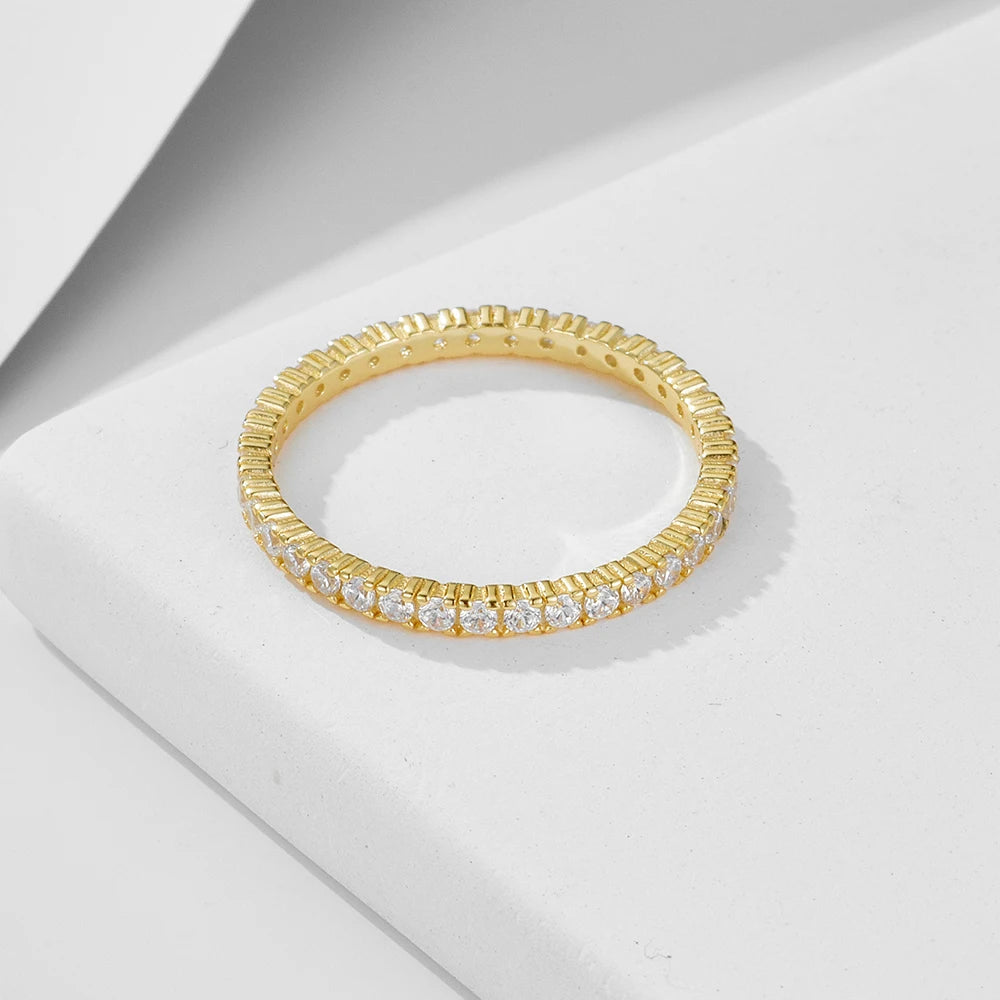 a gold ring set with fine gemstones all around laying on a white surface