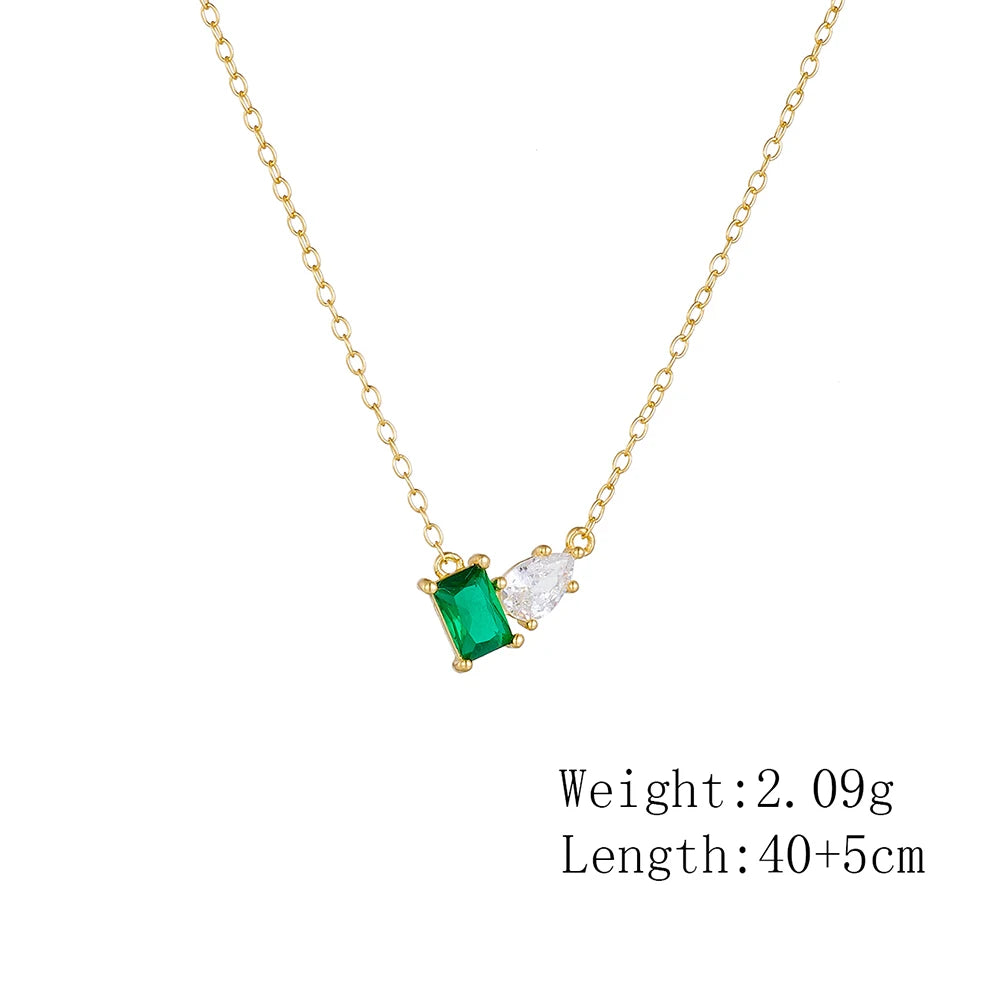 a golden necklace with a green stone and a white stone presented with measurements