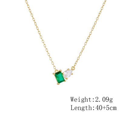 a golden necklace with a green stone and a white stone presented with measurements
