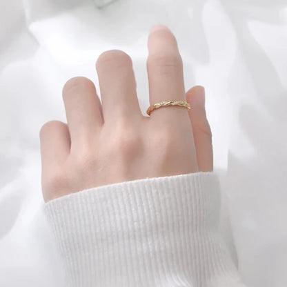 a hand displaying a golden twisted ring on its fingers