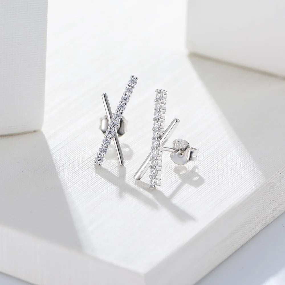 a pair of silver X shaped earrings with gemstones on one cross